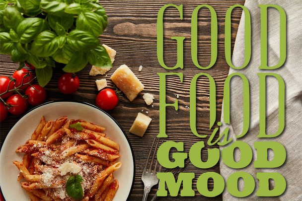 górny widok smaczny makaron bolognese z sosem pomidorowym i Parmesan w białym talerzu w pobliżu składników i sztućce na drewnianym stole, dobre jedzenie jest dobry ilustracja nastroju - Zdjęcie, obraz