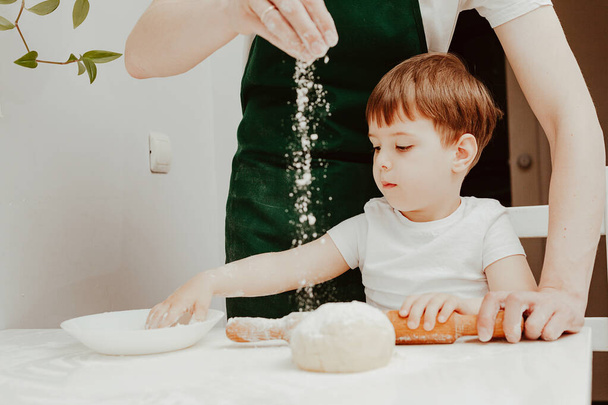 Happy family in the kitchen. Dad and son preparing the dough, bake cookies. Casual lifestyle in home interior, pretty child, holiday concept, rolling pin, coockie cutters and dough.  - Valokuva, kuva