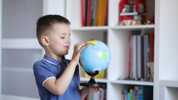 Un niño examina un globo mientras lo sostiene en sus manos
 - Imágenes, Vídeo