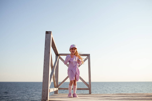 Счастливая симпатичная девушка прогуливается вдоль морского побережья на фоне моря, сзади красивый пейзаж
 - Фото, изображение