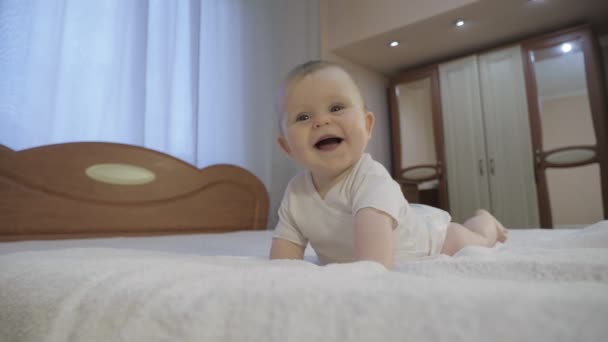 Aranyos baba, kék szemekkel az ágyon fekszik. - Felvétel, videó