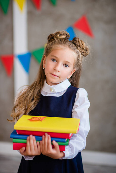 Little girl in a school uniform sits with a globe and books - Zdjęcie, obraz