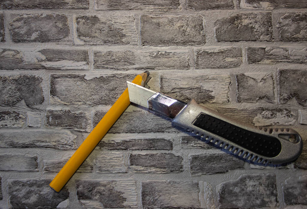 Naostřit žlutou tužku s kancelářským nožem na pozadí cihlového wal - Fotografie, Obrázek