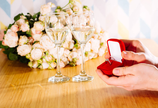 Closeup shot of marriage proposal. Man gives ring with diamond to woman proposing marriage. Indoors restaurant or home, romantic dinner - 写真・画像