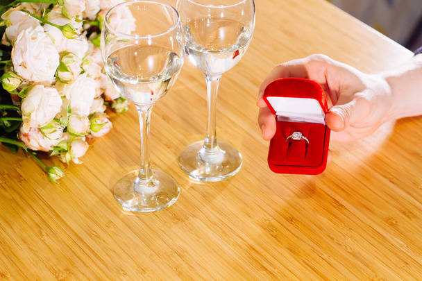 Closeup shot of marriage proposal. Man gives ring with diamond to woman proposing marriage. Indoors restaurant or home, romantic dinner - Foto, immagini