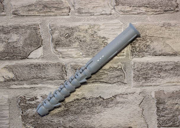 Plugue de âncora com parafuso chave universal contra um wal de tijolo
 - Foto, Imagem