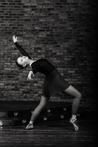 Schöne junge klassische Balletttänzerin auf Spitzenschuhen mit schwarzem Trikot und Rock auf Studiohintergrund - Foto, Bild