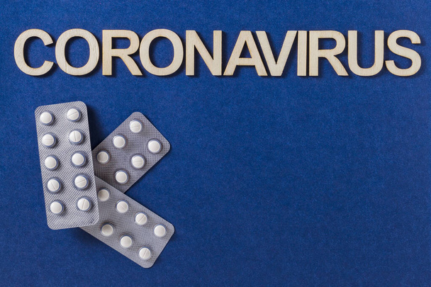 Coronavirus sana kirjoitettu puisilla kirjaimilla ja lääketieteen tabletit, ylhäältä
 - Valokuva, kuva