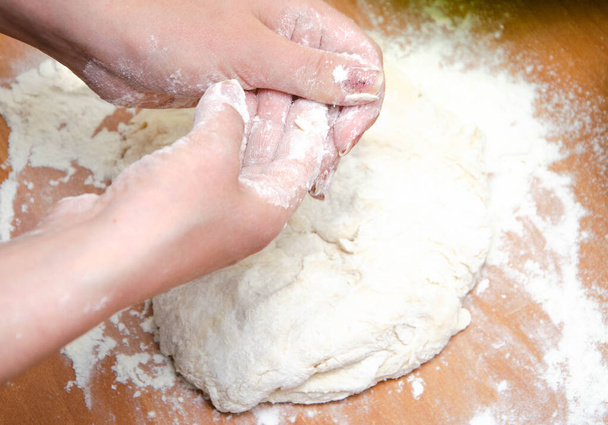 Female hands knead, knead the pizza dough. Dough, flour, cook, pizza. Girl rolls rolling pin dough - Photo, Image