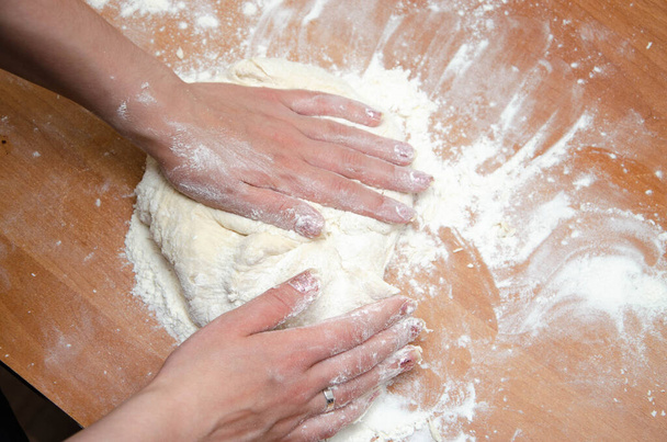 Female hands knead, knead the pizza dough. Dough, flour, cook, pizza. Girl rolls rolling pin dough - Valokuva, kuva