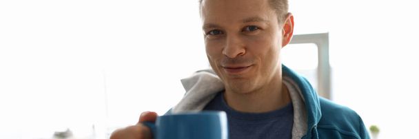 Guy in sportswear at home drinks from big cup - Foto, Bild