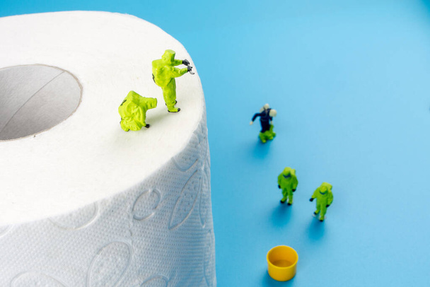 a team of miniature figurines checking a cleanliness of toilet paper, very important to make a desinfection of lavatory and other possibly dirty places in an household - Photo, Image