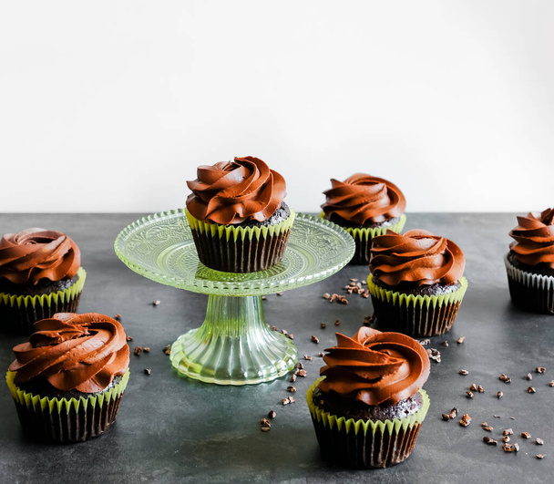 Pastelitos de chocolate negro y plumas de cacao sobre fondo oscuro. Concepto de comida dulce
.  - Foto, Imagen