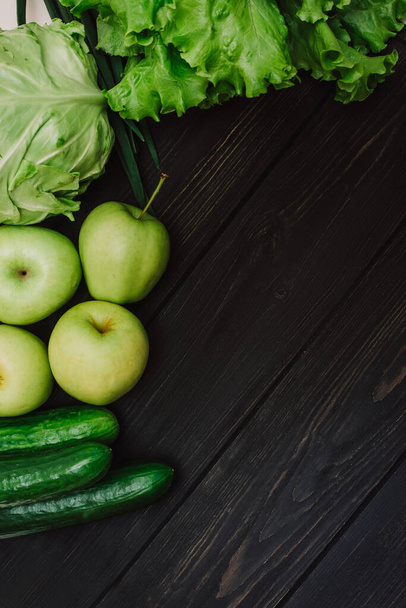 Fresh green organic vegetables and fruits in an eco reusable bag. Cucumbers, cabbage, lettuce, apples on black wooden background. Detox and green dieting. Healthy lifestyle concept. Eco life - Foto, Imagen