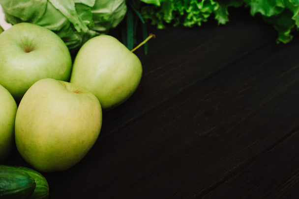 Зеленые экологически чистые овощи и фрукты в экопакете многоразового использования. Огурцы, капуста, салат, яблоки на черном деревянном фоне. Детоксикация и зеленая диета. Понятие здорового образа жизни. Эко-жизнь
 - Фото, изображение