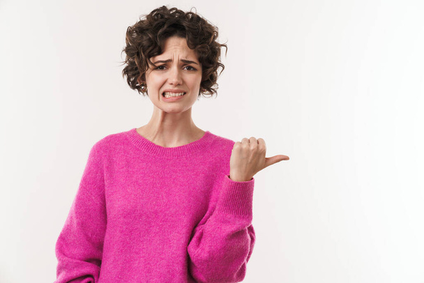 Image of young displeased woman grimacing and pointing finger aside isolated over white background - Photo, image
