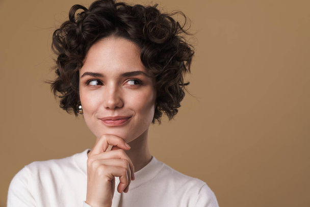 Image of thinking pleased woman posing and looking aside isolated over beige background - Photo, Image