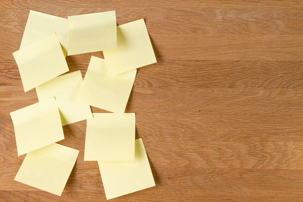 Липкие ноты. Чистые желтые квадратные бумажные наклейки на фоне натуральной деревянной доски
 - Фото, изображение