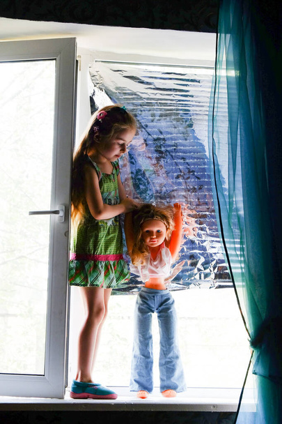 Маленькая девочка у окна. Пятилетняя девочка сидит у окна дома. Детство, дитя, окно. Оставайтесь дома
 - Фото, изображение