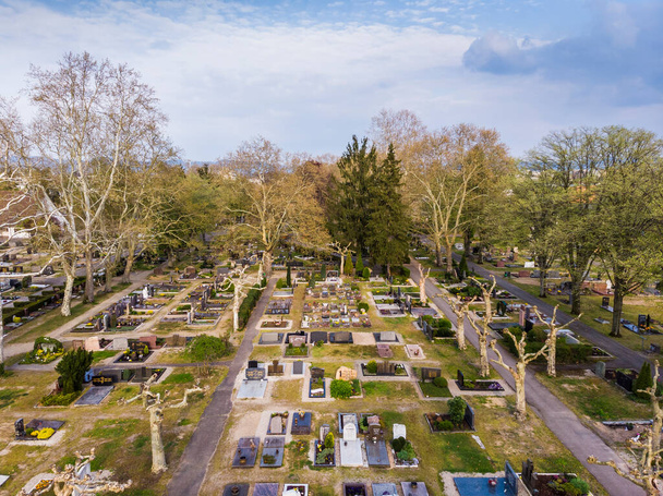 Вид сверху на городское кладбище в Верншафте. Ряды могил. Серые деревья. Германия
. - Фото, изображение