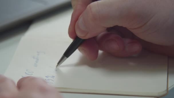 A man writes with a pen in a notebook. Close-up - Felvétel, videó