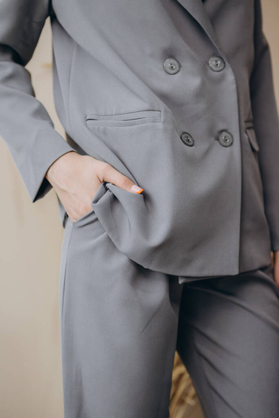 Porträt einer attraktiven blonden Frau posiert für die Werbung eines Damenbekleidungsgeschäfts in grauer Jacke und Hose mit Bluse - Foto, Bild