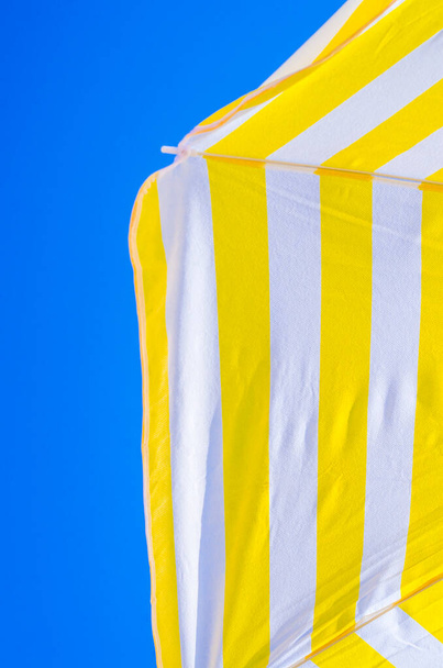 sárga és fehér esernyők a kék ég a háttérben, három szín szimbólumok a nyár, mint a festmények - Fotó, kép