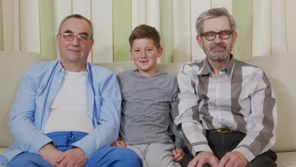 Twee grootvaders met een kleinzoon op een bank. - Video