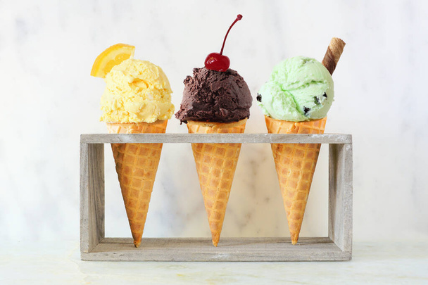 Fagylaltkúp választék gofri tölcsérben fehér márvány háttér mellett. Citrom, csokoládé és menta ízesítéssel. - Fotó, kép