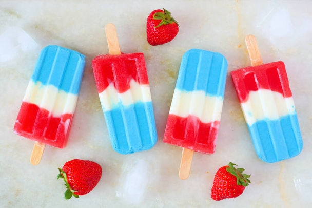 Rood, wit en blauw zomer fruit ijs pops. Bovenaanzicht op een witte marmeren achtergrond. - Foto, afbeelding