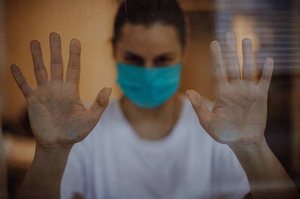 selective focus, noise effect: woman wearing a medical mask during a pandemic of viral diseases is quarantined at home - Fotoğraf, Görsel
