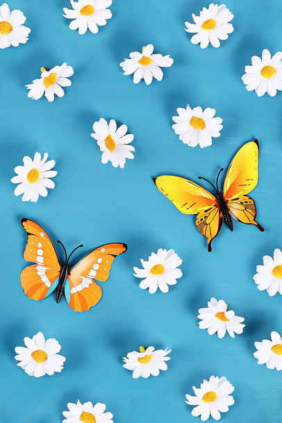 Yellow and orange butterflies and daisies on a blue background. Top view. Summer background. Flat lay. - Foto, Imagem