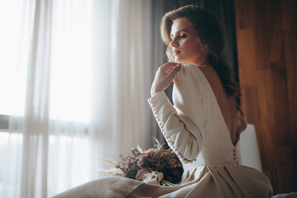 Bride Preparation: Delicate photos of a blond bride woman getting ready for her first date with the bride. Stylish wedding dress and sensual girl with perfect model look - 写真・画像