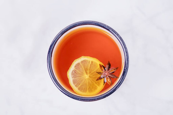 Šálek citrónového čaje s anýzovou hvězdou na bílém mramorovém pozadí. Horní pohled, kopírovací prostor, minimální styl - Fotografie, Obrázek