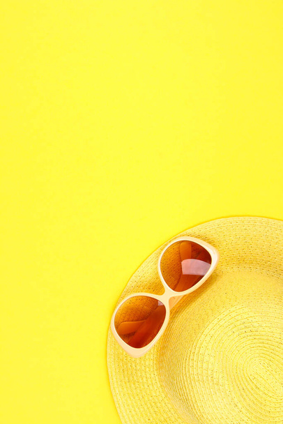 Hat, sunglasses on a pastel yellow background - Foto, imagen