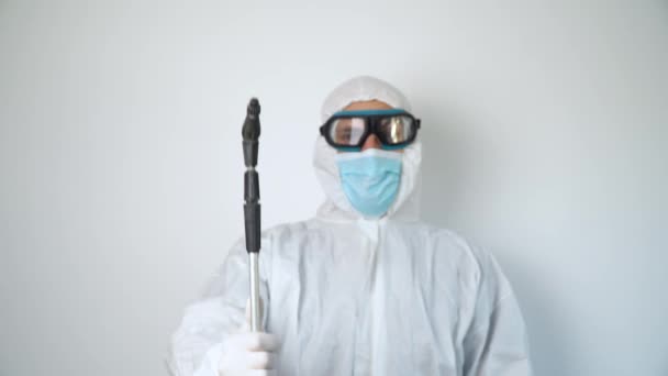 Virolog, koronavirüs salgını sırasında koruyucu giysiler giyip portre yapıyor. Klinikte ya da hastanede beyaz arkaplanda takım elbise, maske, eldiven ve gözlük - Video, Çekim