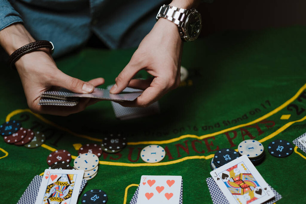 Croupier holds playing cards, game chips on the table. - Photo, Image