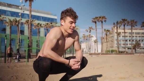 Giovane uomo muscoloso attraente che riposa dopo un duro allenamento sul campo sportivo sulla spiaggia di Barcellona - Filmati, video