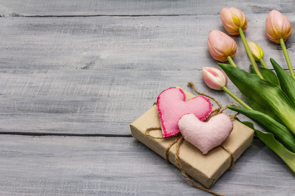 Greetings card, wallpaper, backdrop. Happy Mothers Day, St.Valentines or Wedding. Gentle pink tulips, handmade felt heart, zero waste packaging gift. Wooden boards background - Photo, Image
