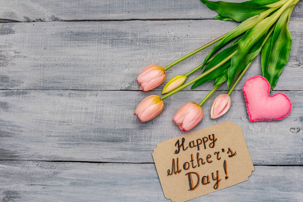 Kartka z pozdrowieniami na Dzień Matki. Delikatne różowe tulipany, ręcznie robione serce filcu, zero odpadów opakowanie prezent. Drewniane tło desek - Zdjęcie, obraz