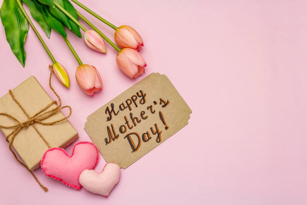 Glückwunschkarte zum Muttertag. Sanft rosa Tulpen, handgemachte Filzherzen, Null-Abfall-Verpackungsgeschenk auf rosa Hintergrund - Foto, Bild