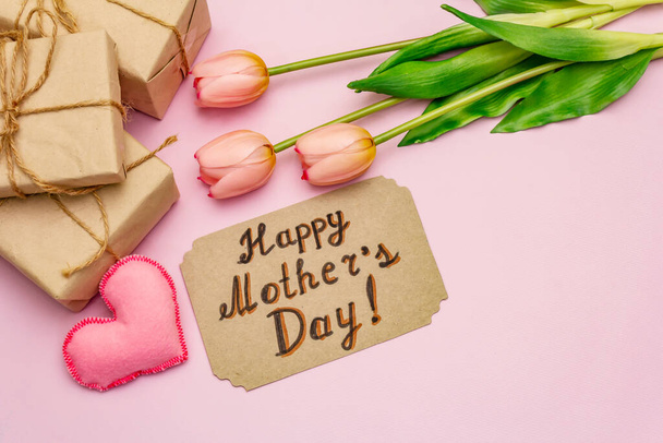 Glückwunschkarte zum Muttertag. Sanft rosa Tulpen, handgemachte Filzherzen, Null-Abfall-Verpackungsgeschenk auf rosa Hintergrund - Foto, Bild
