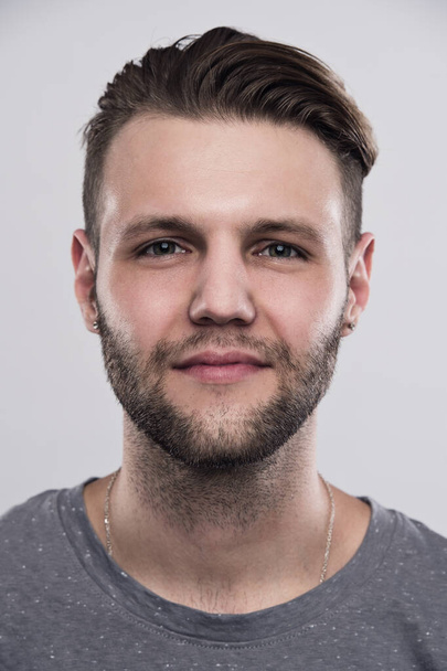 Close up portrait of serious gloomy bearded man with stylish hairstyle posing against white background - Fotoğraf, Görsel