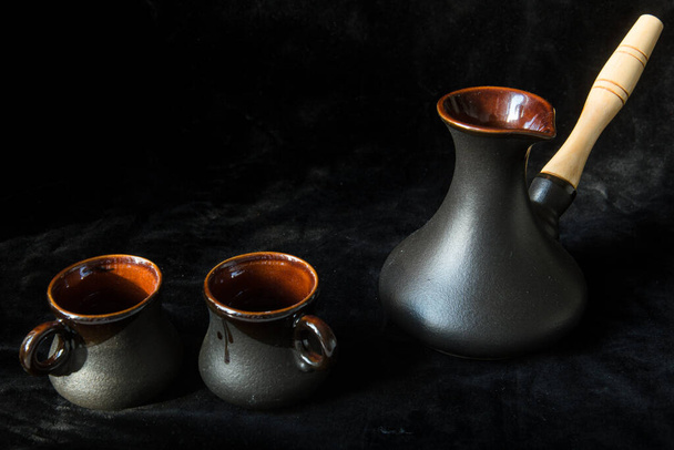 Two black cups for coffee and black turk isolated on black background, place for text. Sweet home - Photo, Image