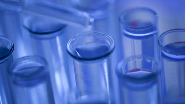 実験室では、ピペットを持った科学者が青色の液体を分析し、試験管内のDNAと分子を抽出します。液体を扱う医者. - 映像、動画