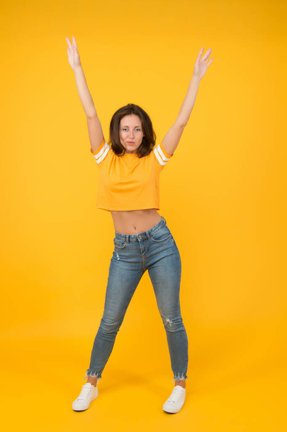 Hands up. Sexy woman yellow background. Pretty woman in casual style. Sensual woman with beauty look. Sexi woman with long brunette hair. Fashion and style. Beauty salon. Womens clothing store - Foto, imagen