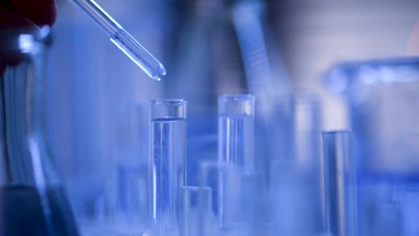 Dans un laboratoire, un scientifique muni d'une pipette analyse un liquide bleu pour extraire l'ADN et les molécules dans les éprouvettes. Médecin travaillant avec du liquide
. - Séquence, vidéo