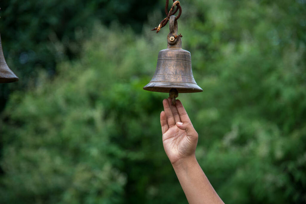 Piękna młoda dziewczyna dzwoni wielkim dzwonkiem w świątyni. - Zdjęcie, obraz