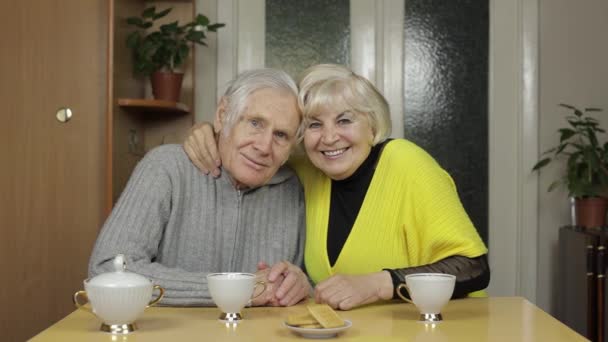 Happy old grandparents couple sit on table at home enjoy drinking tea together - Footage, Video