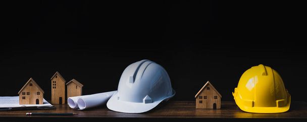 real estate, property and construction project concept, engineer's tools with small wooden house or home on table in dark background  - Photo, Image
